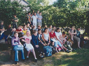 Schler sitzen auf Baumstmmen zum Gruppenfoto