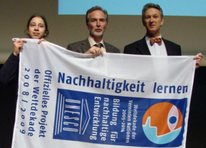 Schler und Mitarbeiter halten stolz das Banner der Auszeichnung des Dekade Projektes