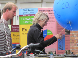 Zwei Menschen betrachten einen groen blauen Luftballon, der ber einem Stadtmodell der Hansestadt Stralsund angebracht ist und die Aufschrift CO2 trgt.