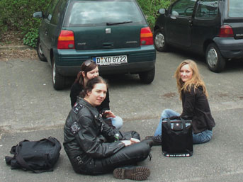 Schüler sitzen auf dem Parkplatz vor den Autos