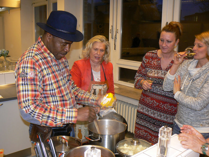Das Foto zeigt drei Frauen und einen Mann beim Kochen.