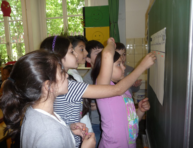 Das Foto zeigt Schülerinnen, die Klebepunkte auf einen an der Wandzeitung hängenden Zettel kleben. Sie bewerten damit ihr ejeweilige Lieblingssportart vom Sportfest der Schule.
