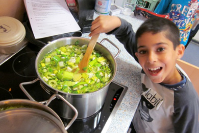 Das Foto zeigt einen Jungen, der Suppe kocht.
