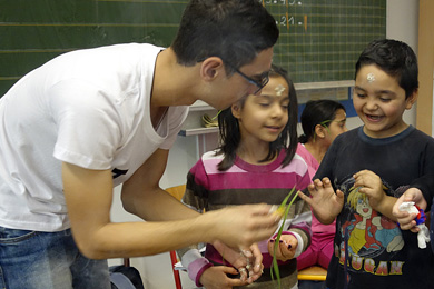 Das Foto zeigt einem Mann und zwei Schüler in einem Klassenraum.