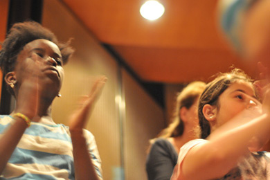 Das Foto zeigt singende Kinder in einer Konzerthalle.