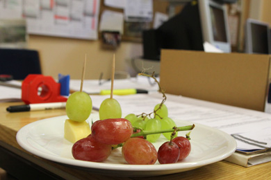 Das Foto zeigt einen Teller mit Obst und Käse auf einem Arbeitstisch im Lehrerzimmer