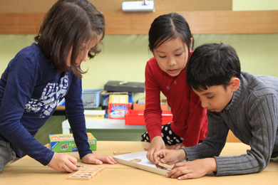 Das Foto zeigt zwei Mädchen und einen Jungen, die gemeinsam Mathe lernen.