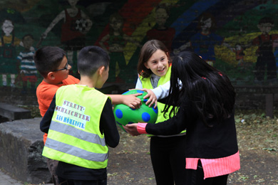 Das Foto zeigt zwei Kinder, die sich um einen Ball streiten und zwei weitere, die versuchen, diesen Streit zu schlichten.