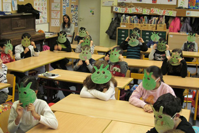 Das Foto zeigt Kinder in einem KLassenraum mit grünen Masken.
