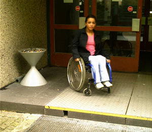Rollstuhlfahrerin an der Stufe am Seitenausgang