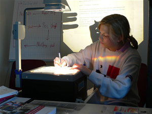 Schülerin am Lichtprojektor schreibt an die Tafel