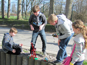 Das Foto drei Schüler und eine Schülerin, die im Freien mit einer kleinen Maschine experimentieren. Die Maschine ist aus Lego gebaut und wird mit der Sonnenenergie angetrieben.