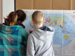 Das Foto zeigt zwei Jugendliche, die intensiv eine Weltkarte betrachten.