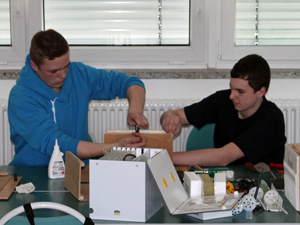 Das Foto zeigt zwei Jungen, die ein Hausmodell bauen.