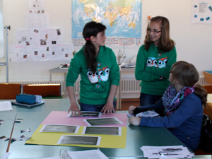Das Foto zeigt drei Mädchen, die eine Wandzeitung zum Thema Abfall erstellen.