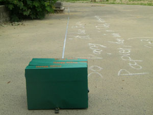 Das Foto zeigt eine grüne Kiste, die auf einer Betonfläche steht.