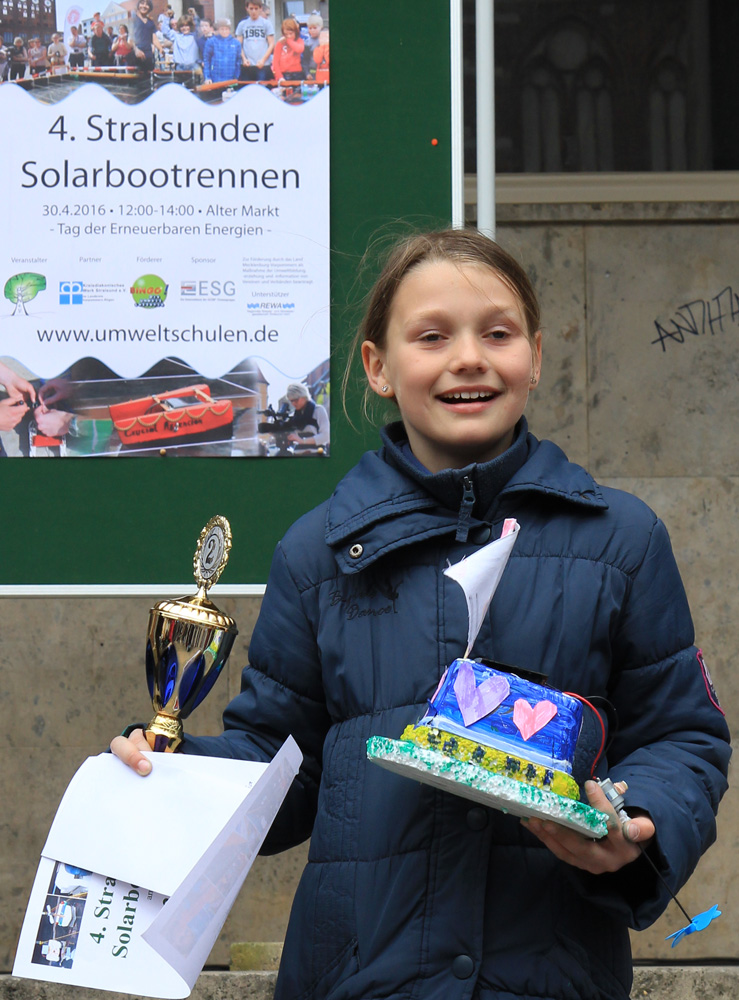 Das Foto zeigt eine Schülerin mit Solarboot, Urkunde und Pokal.