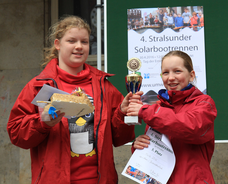 Das Foto zeigt zwei Schülerinnen mit Solarboot, Urkunde und Pokal.