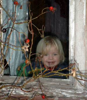 Ein Kind schaut aus einem maroden Fenster