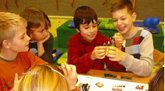 Das Foto zeigt einige Grundschüler, die mit sichtlicher Freude mit Batterien, Drähten und Glühlampen experimentieren.