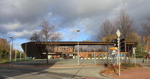 Das Foto zeigt das MÜritzeum Waren, einen großen ovalen Flachbau mit einer Glasfassade.