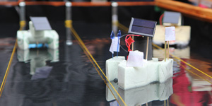 Das Foto zeigt drei kleine Solarboote auf einem Wasserbecken.