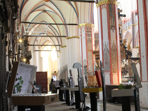 Das Foto zeigt das Innere einer großen gotischen Kirche, im Vordergrund sind einige Ausstellungsexponate - große Koffer auf Tischchen - zu sehen.