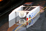 Das Foto zeigt ein kleines Boot - einen Katamaran - der aus Schaumpolystyrol gebaut wurde und mit einer Solarzelle, einem Motor und einer Schiffsschraube als Antrieb ausgestattet ist.