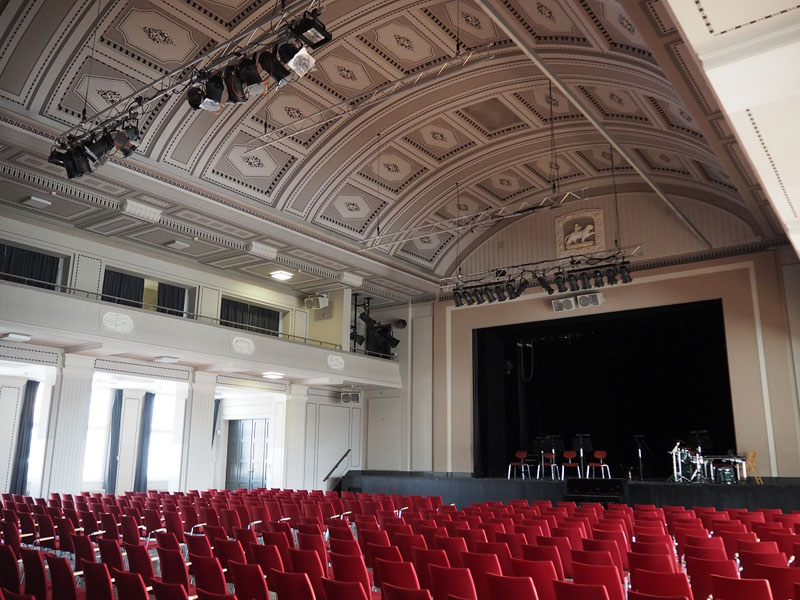 Das Foto zeigt die Stadthalle Greifswald von innen - einen großen Saal mit roten Stühlen.