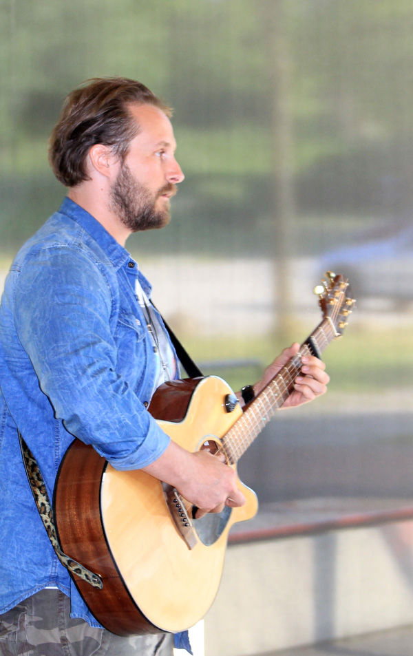 Das Foto zeigt einen singenden Mann mit Gitarre.
