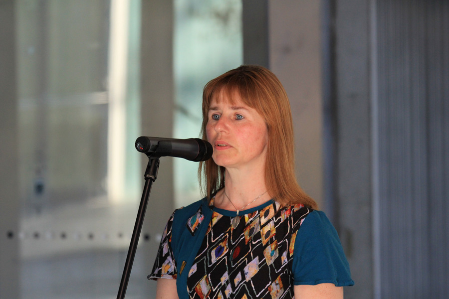 Das Foto zeigt das Brustbild einer Frau, die in ein Mikrofon spricht.