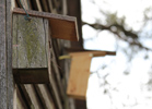 Das Foto zeigt zwei Nistkästen aus Holz, die an einer aus Holz gefertigten Außenwand einer Scheune hängen.
