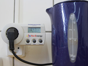 Das Foto zeigt einen elektrischen Wasserkocher, der an ein Energiekostenmessgerät angeschlossen ist. Dieses zeigt einen Wert von 1847 Watt an - die aktuelle Leistung bzw. der aktuelle Stromverbrauch des Wasserkochers.